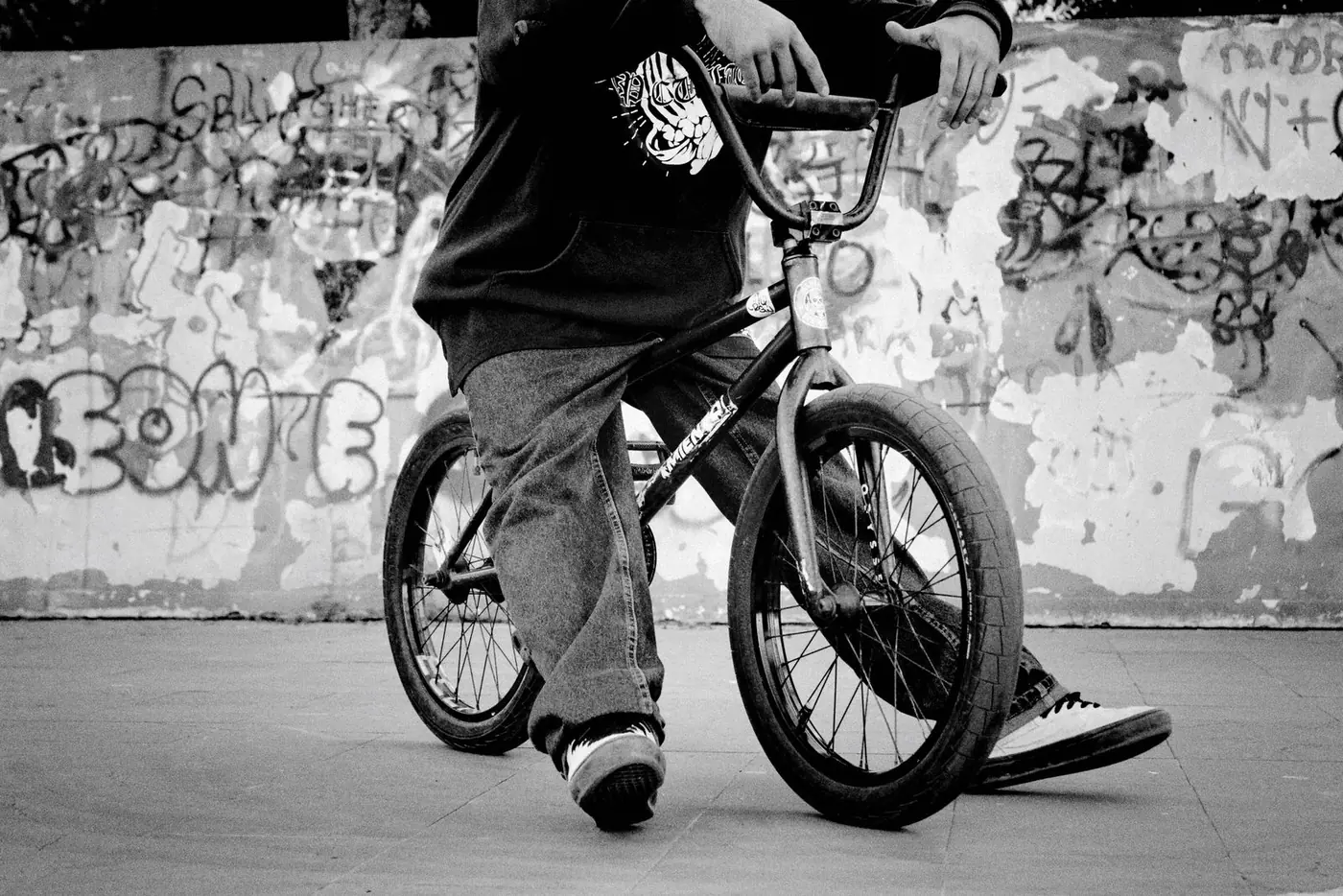 Adulte assis sur un vélo BMX devant un mur de graffitis