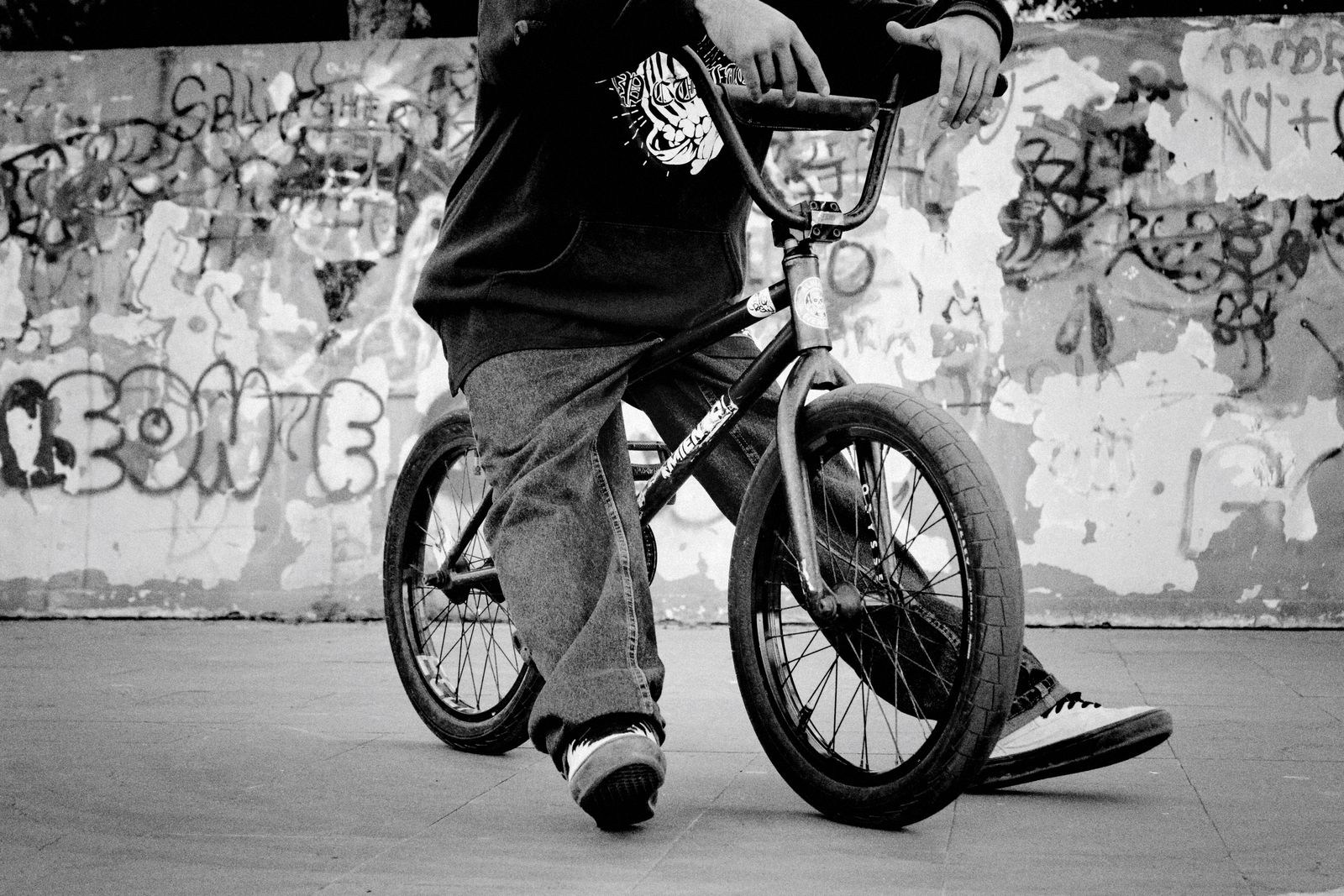 Adulte assis sur un vélo BMX devant un mur de graffitis