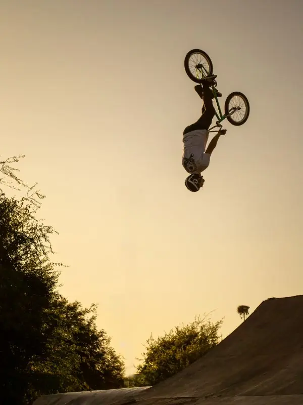 Rider de BMX la tête en bas pendant un backflip au coucher du soleil