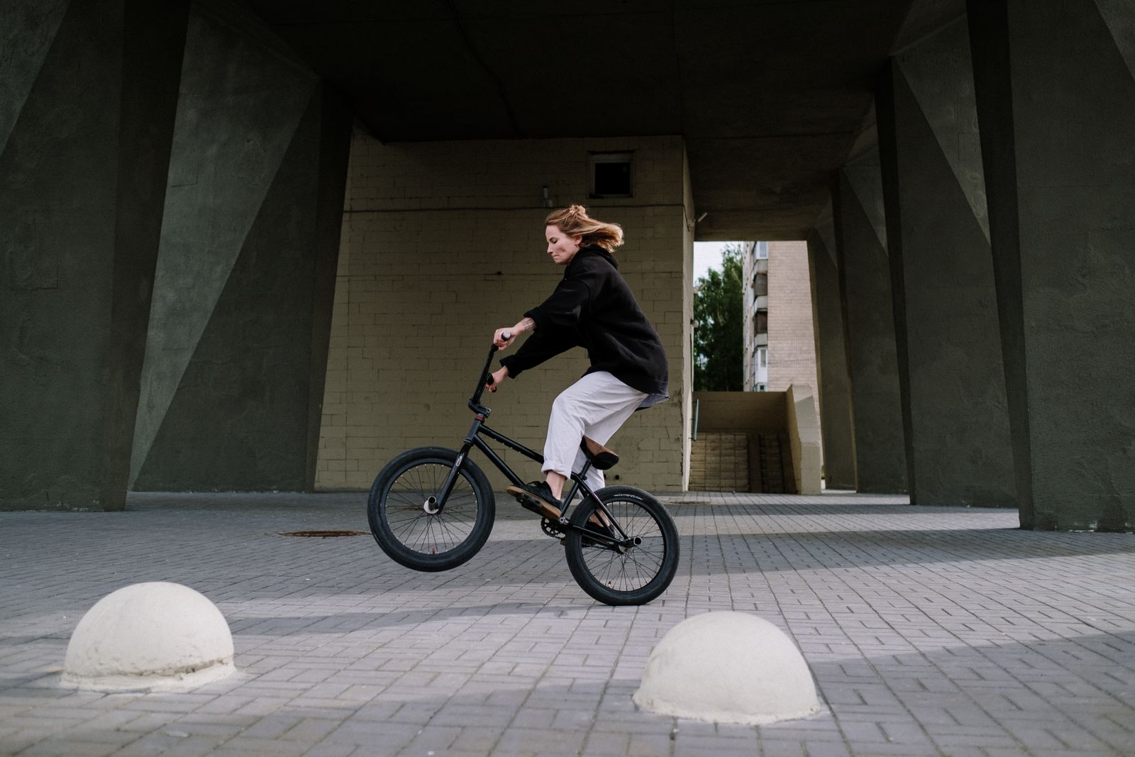 Rideuse réalisant une figure d'équilibre en BMX sur un sol plat