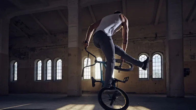 Rider de BMX freestyle en figure sur la roue avant dans un bâtiment industriel