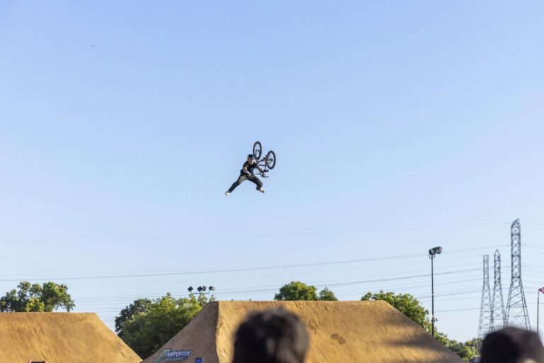 Rider de BMX freestyle réalisant une figure aérienne très haut au-dessus des rampes (photo d'illustration)