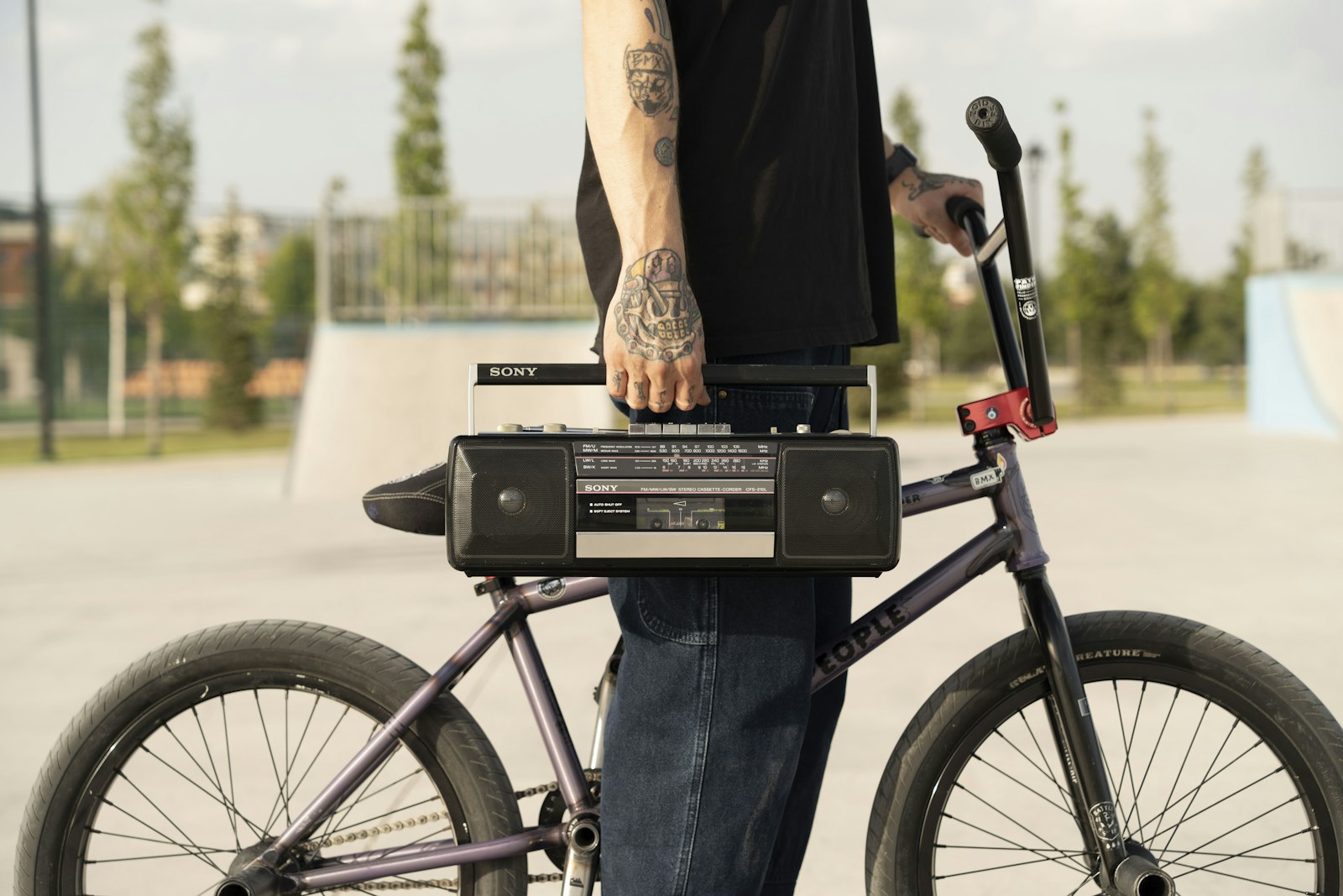 Rider tenant un radiocassette à côté d'un BMX dans un skatepark, ambiance old school