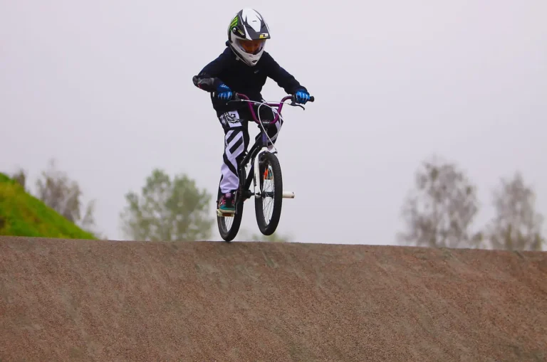 Pilote de BMX Race dévalant une pente sur une piste en terre