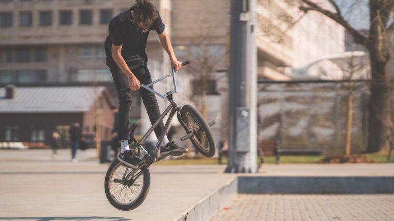 Rider de BMX levant la roue avant de son vélo sur une place en ville
