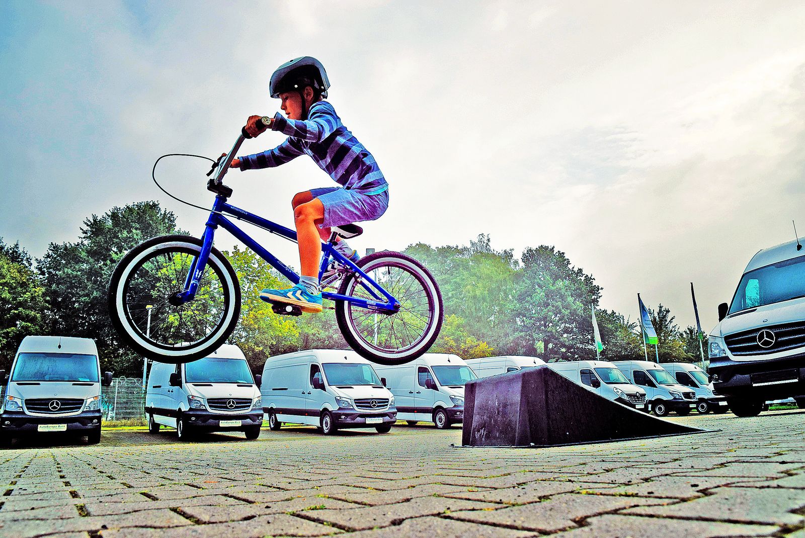 Enfant réalisant un saut en BMX sur un parking