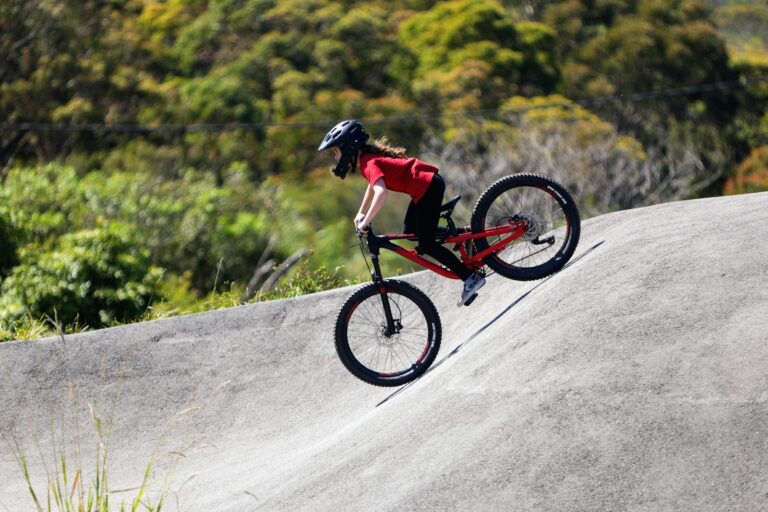 Jeune rider casqué à vélo dans un virage relevé de pumptrack en enrobé