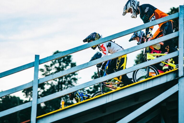 Pilotes de BMX Race en casque intégral alignés sur la grille de départ, vus en contre-plongée