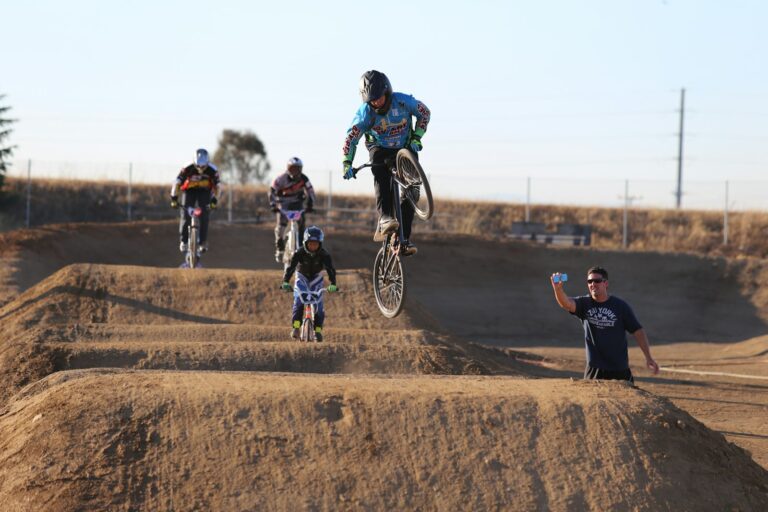 Pilotes de BMX Race franchissant les bosses d'une piste en terre