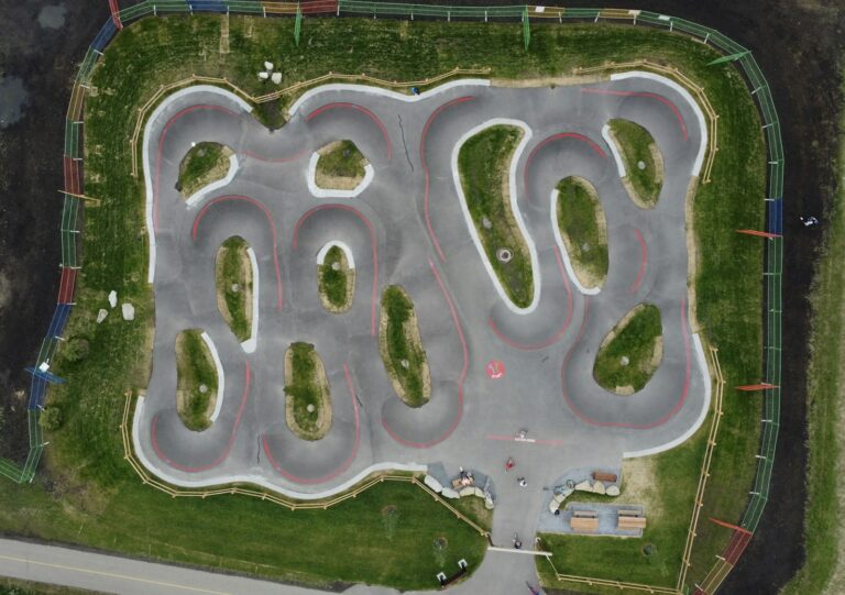 Vue aérienne d'un grand pumptrack en enrobé avec ses boucles, bosses et virages relevés