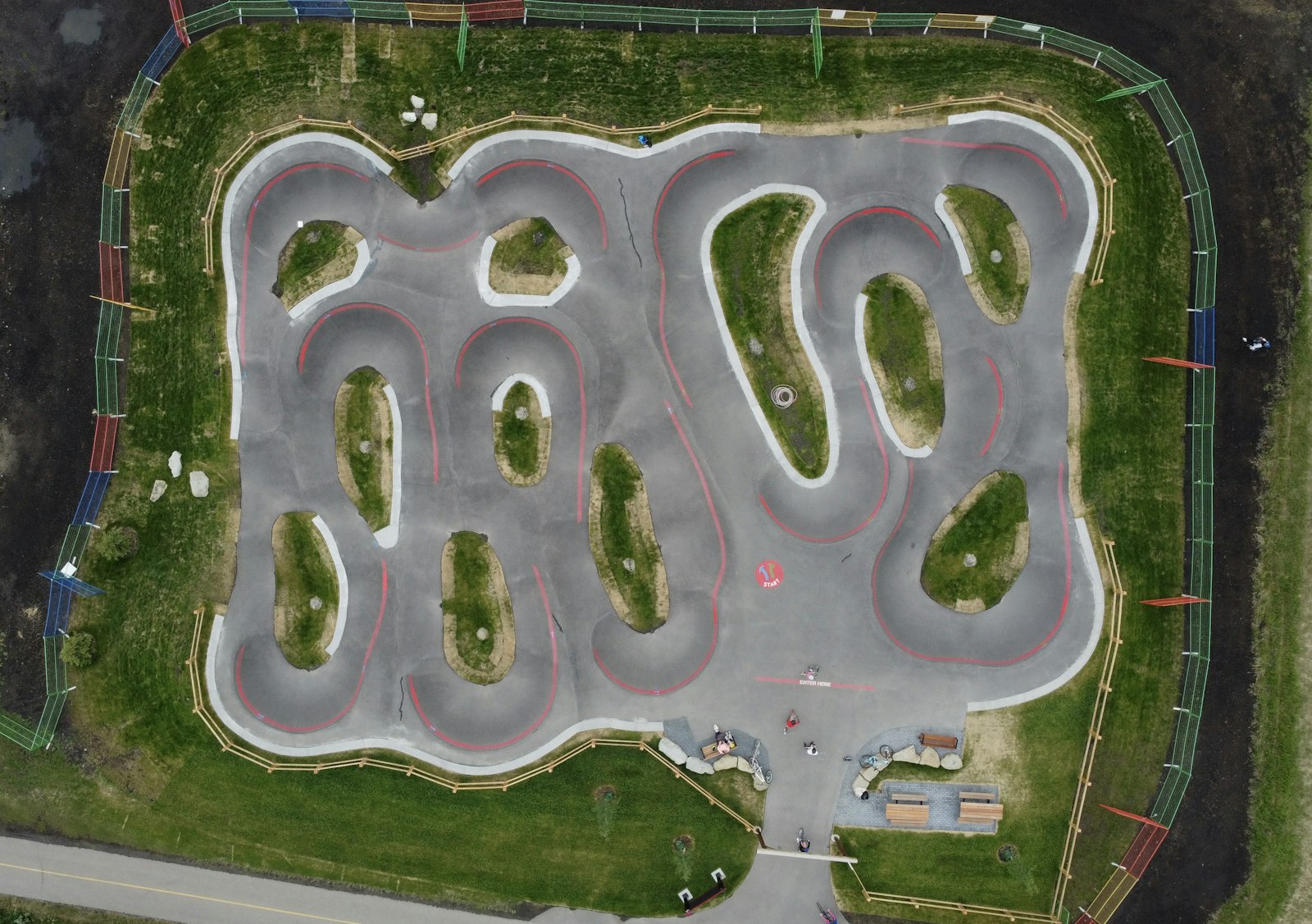 Vue aérienne d'un grand pumptrack en enrobé avec ses boucles, bosses et virages relevés
