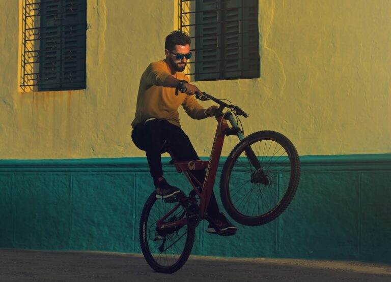 Rider en wheeling sur la roue arrière de son vélo devant un mur coloré